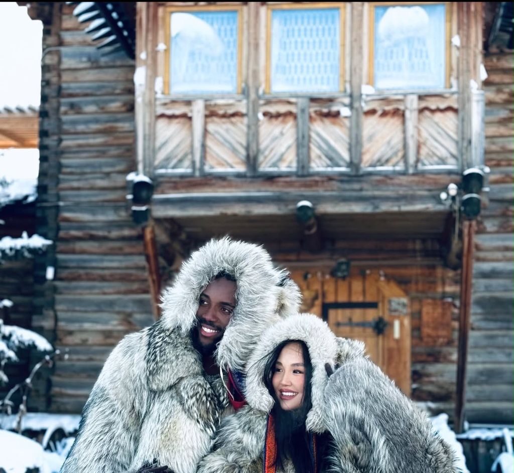 Guests dressed in traditional Sakha fur coats in front of a wooden house