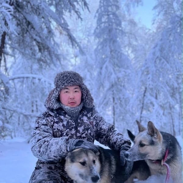 Musher with two husky sled dogs in the snowy forest